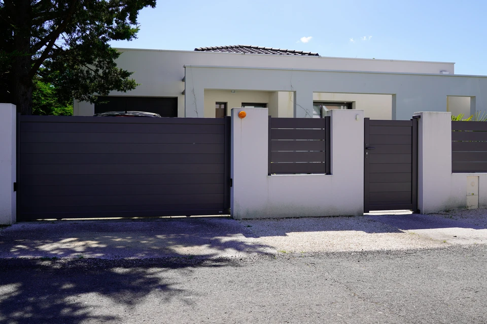 Extérieur résidentiel avec maison moderne blanche à toit plat et portail coulissant anthracite