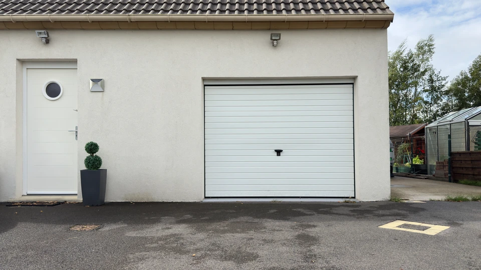 Maison résidentielle avec garage moderne avec une porte en section en face du paysage en été