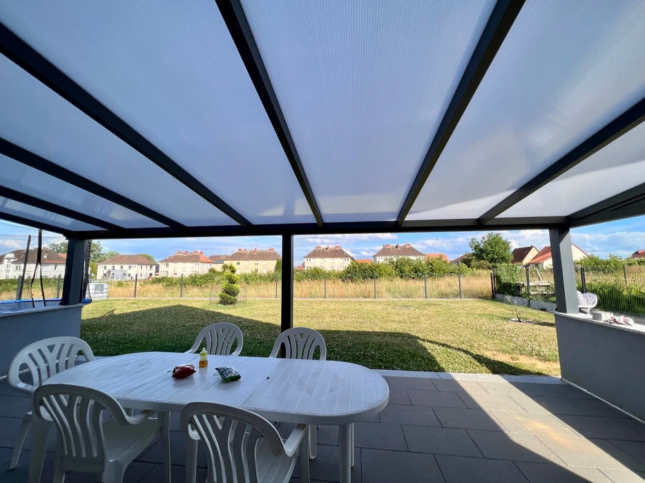 Façade arrière d'une maison contemporaine avec terrasse en bois, baies vitrées et mobilier d'extérieur