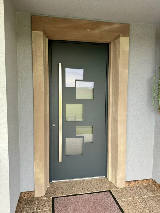 Entrée d'habitation moderne avec porte d'entrée anthracite équipée d'un vitrage vertical central décoratif
